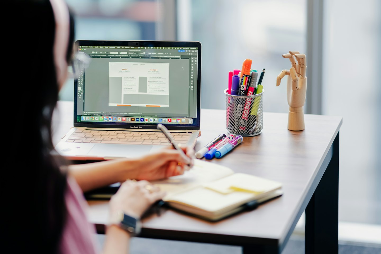 Woman with dark hair designs on a laptop at her desk.